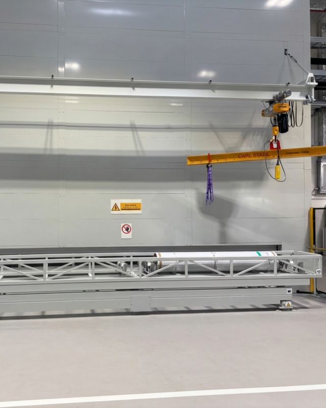 Plně opláštěná instalace Long Span Tower s integrovaným jeřábovým systémem pro nakládku a vykládku těžkých válcových materiálů ve výrobním prostředí.